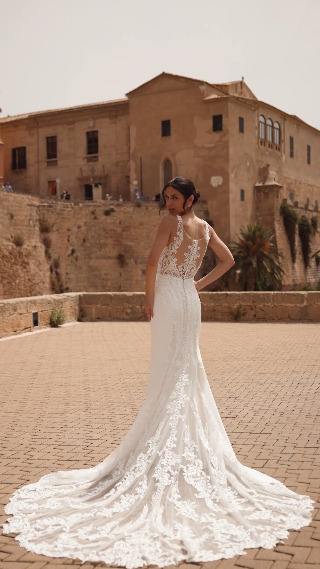 Bride Wearing A Fitted Crepe Wedding Dress With Illusion Back and Cutout Lace Train