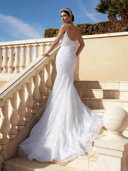 A radiant bride ascends the stairs, donning Moonlight Couture H1584 a beaded tulle mermaid bridal gown the dress showcases delicate beaded off-the-shoulder straps.