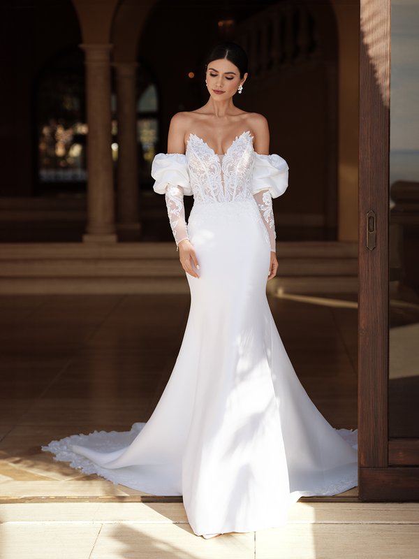 A stunning bride dons Moonlight Couture H1589 an strapless wedding dress, featuring exquisite lace details, a pointed sweetheart neckline, and delicate puff illusion long sleeves
