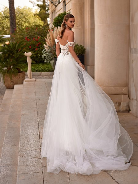 Back view of a bride walking away in a wedding gown with tulle Watteau train and illusion back with buttons and loops