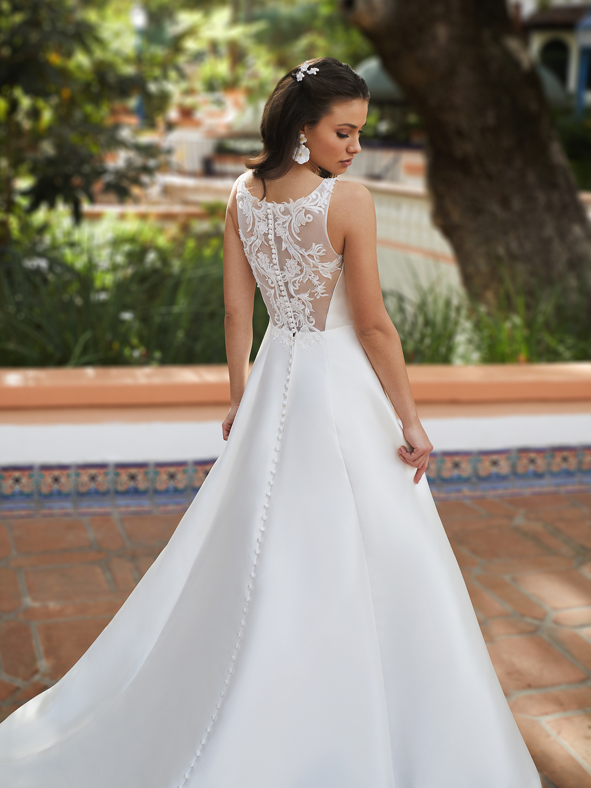 Bride looking over her shoulder wearing a simple, elegant wedding gown with an illusion bateau back