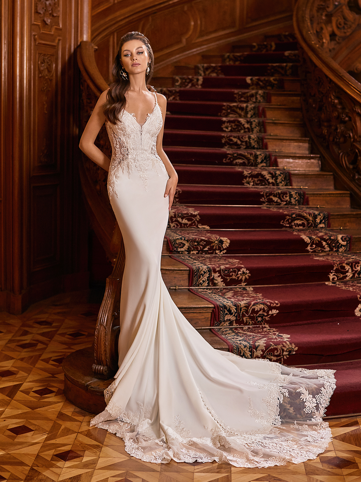 Tall woman wearing a mermaid wedding dress standing next to wooden staircase