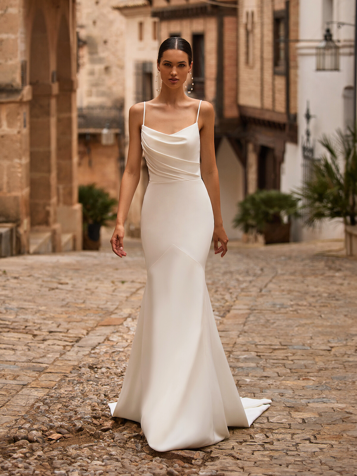 Woman walking forward wearing a mermaid wedding dress with scoop neck. 