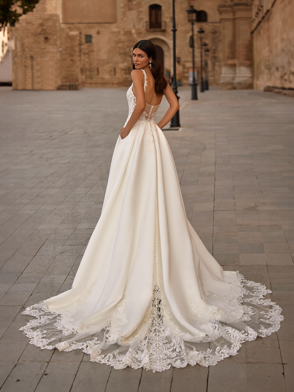 Woman wearing simple and elegant satin ball gown with hands in the pockets. 