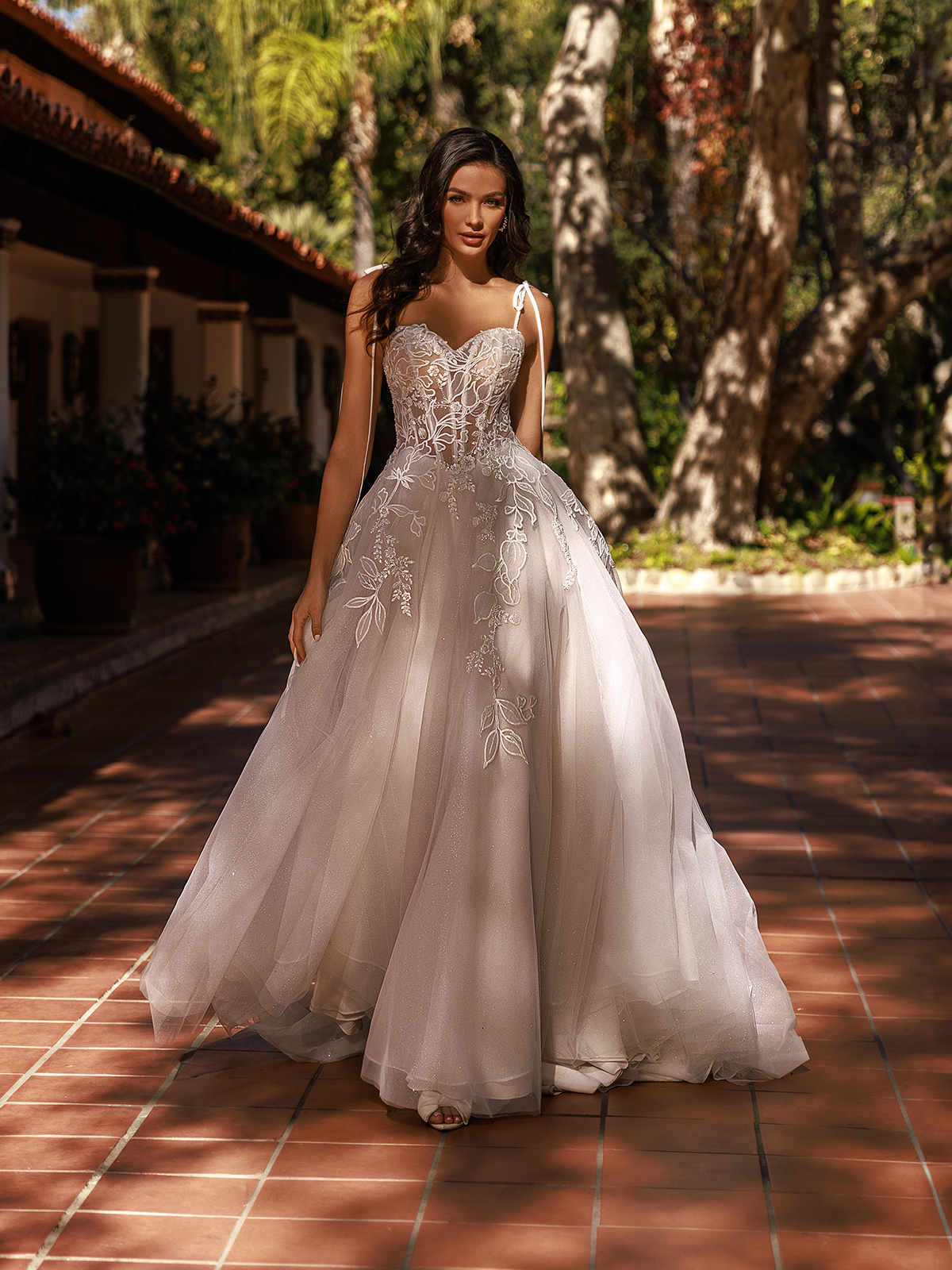Woman standing outdoors wearing a tulle and sparkle tulle wedding dress with a stunning lace bodice