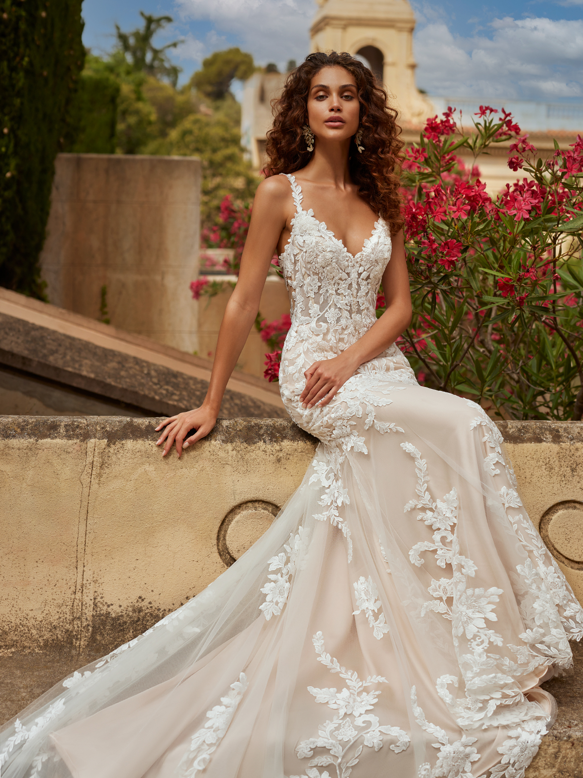 Woman sitting outside wearing a lace bridal dress with lace spaghetti straps