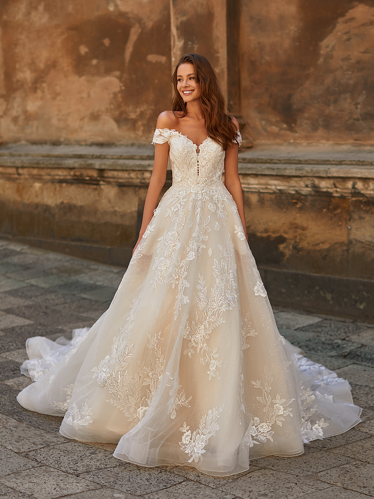 Bride walking outside in an A-line wedding dress with off-the-shoulder sleeves