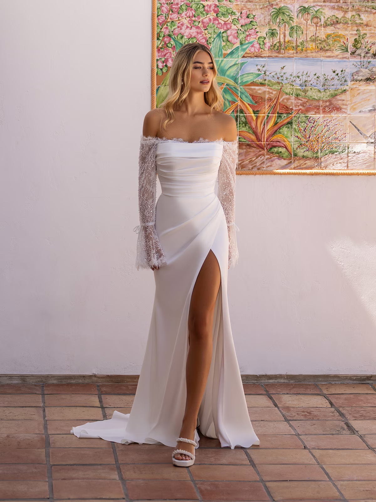 Woman standing outside in a lace and crepe wedding gown with flowing bell sleeves