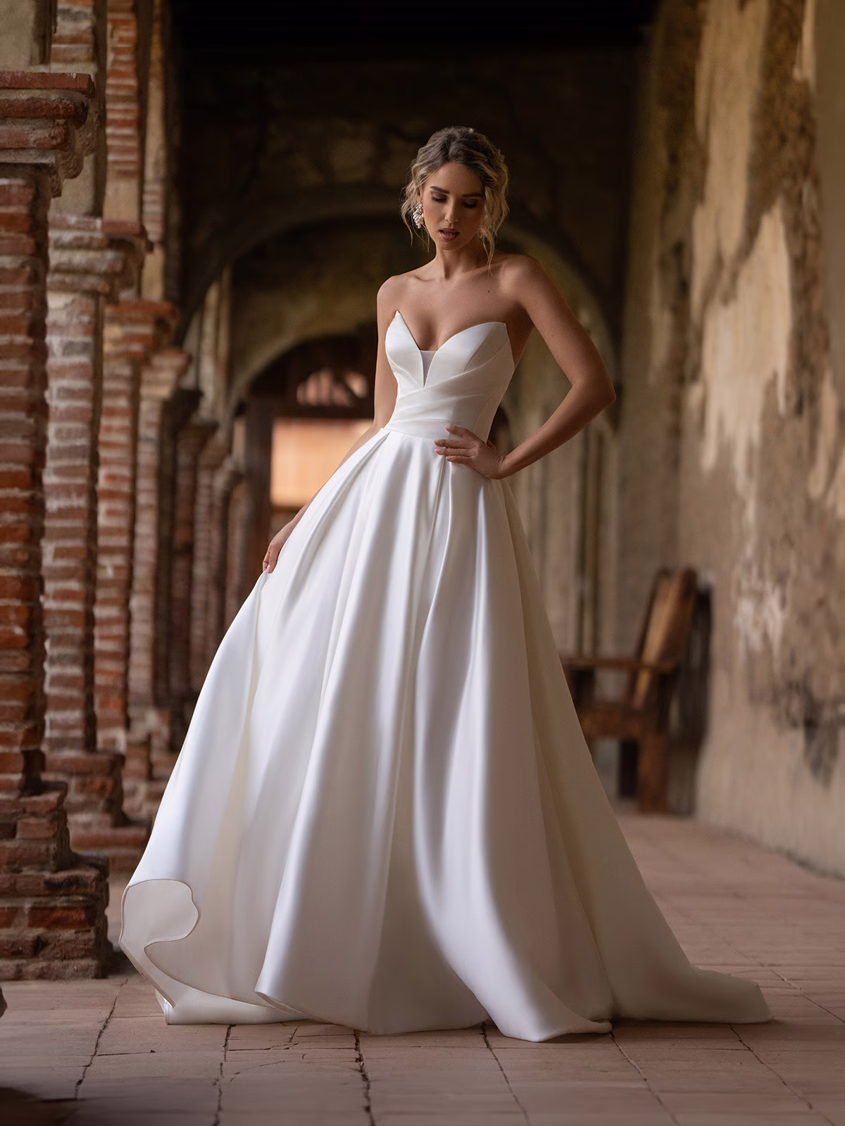Woman wearing a classic stain ball gown wedding dress walking through an outdoor venue