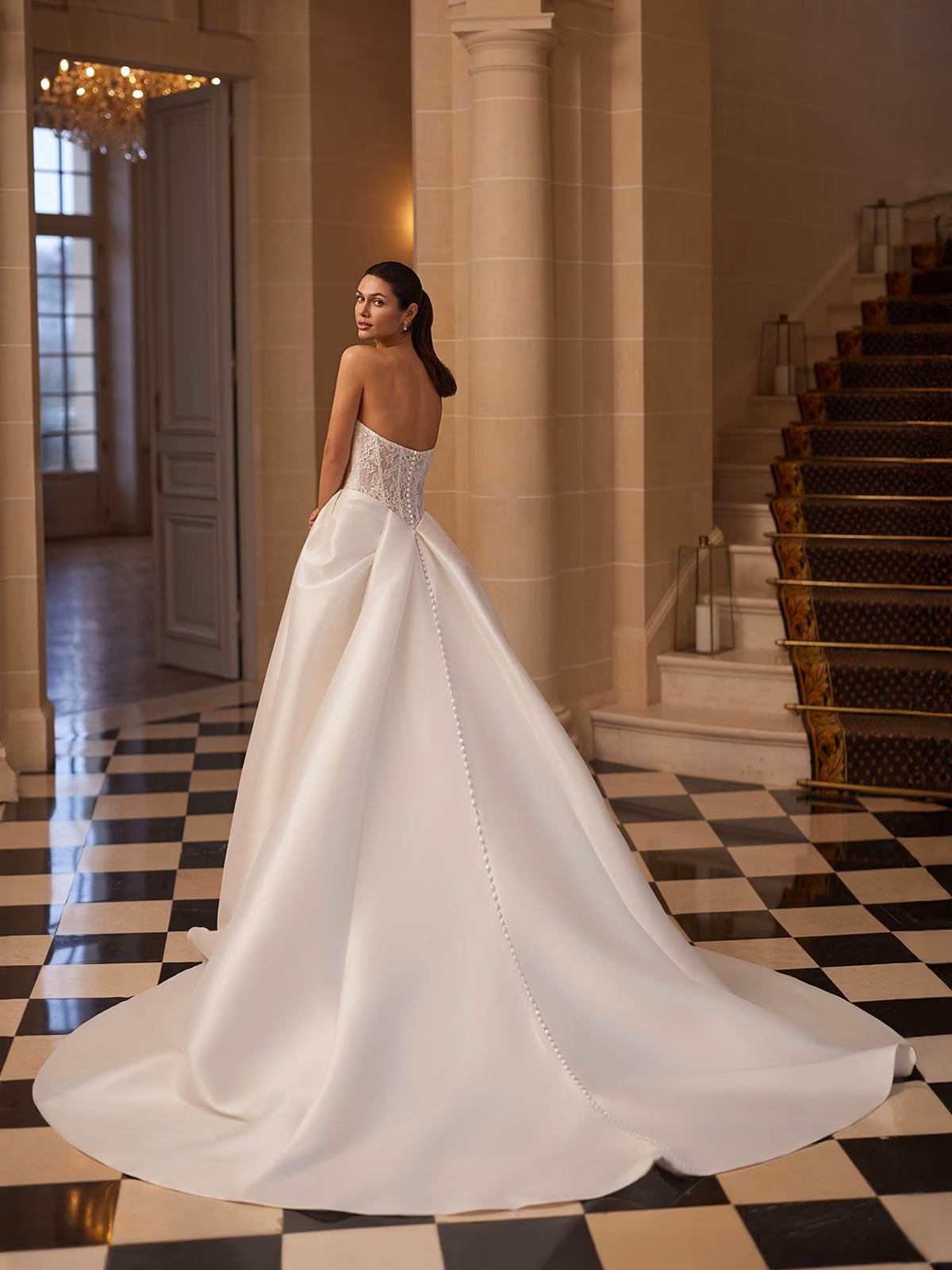 A bride in Moonlight Couture H1656 Illusion open back A-line with buttons along zipper continue to end of chapel train