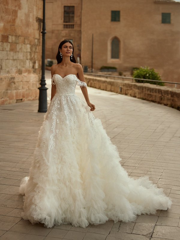 Bride Wearing An Ivory A-line Wedding Dress With Ruffles and Off The Shoulder Sleeves