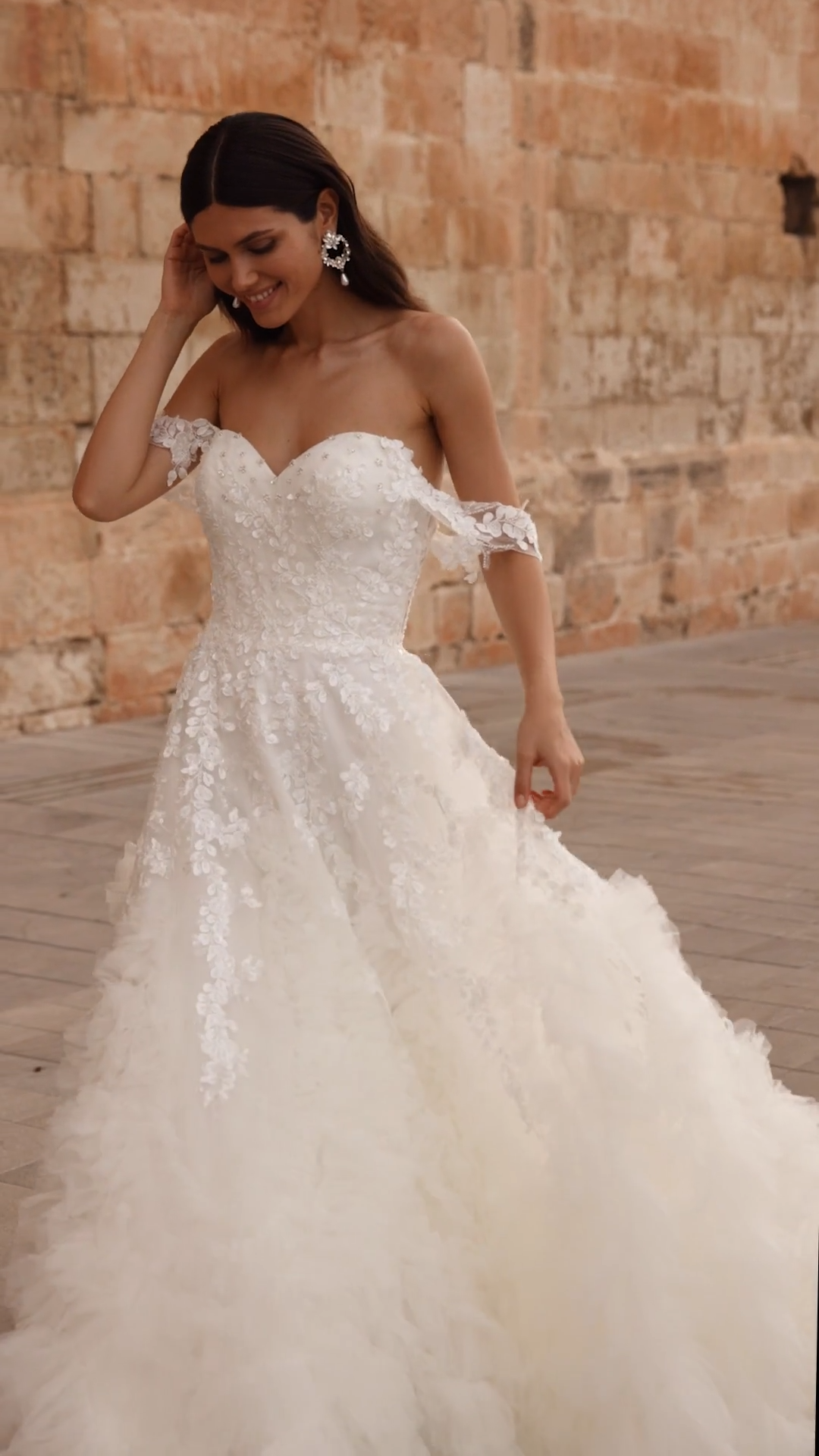 Bride Walking In Ruffled A-line Wedding Dress With Beading Along Sweetheart Neckline and Off The Shoulder Sleeves