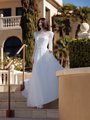 A vision of elegance, a bride in Moonlight Couture H1586 a high neck pearl-beaded A-line wedding dress, gracefully descending a staircase.