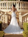 A stunning bride in Moonlight Couture H1591 an exquisite mermaid drop waist wedding dress, adorned with 3D florals. She stands gracefully on a grand staircase