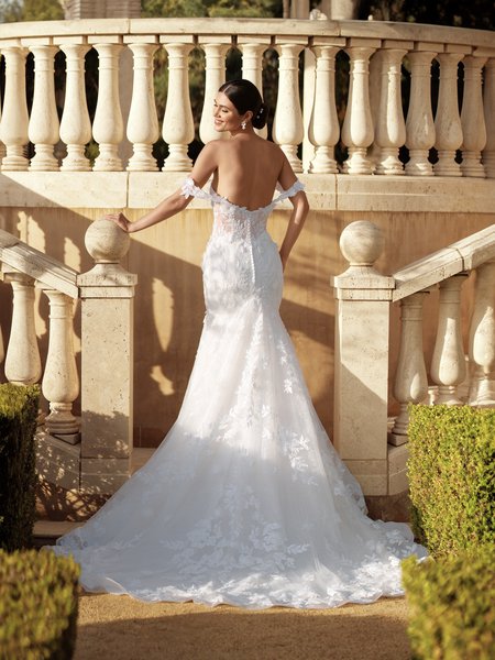 A stunning bride in Moonlight Couture H1591 an exquisite mermaid drop waist wedding dress, adorned with 3D florals. She stands gracefully on a grand staircase