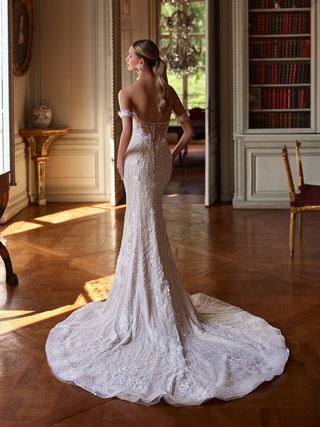 The back of a bride in a stunning illusion open back elaborately beaded wedding dress, poised in a beautifully adorned room The back of a bride in a stunning illusion open back elaborately beaded wedding dress, poised in a beautifully adorned room