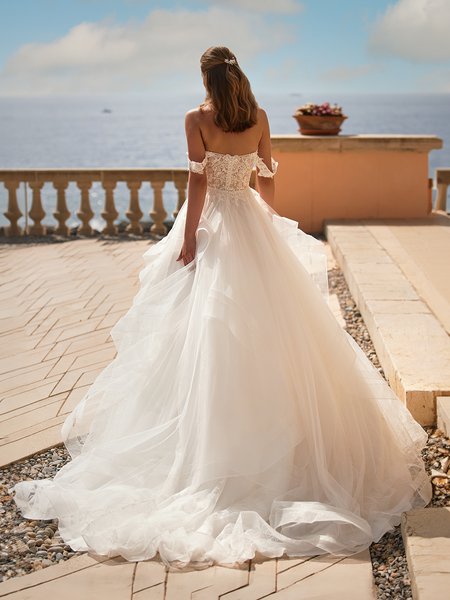 Bride Walking Towards Balcony In Chapel Train Wedding Dress With Cascades and Illusion Open Back