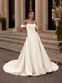 Bride next to staircase in classic satin A-line wedding dress with off the shoulder pleated swag sleeves