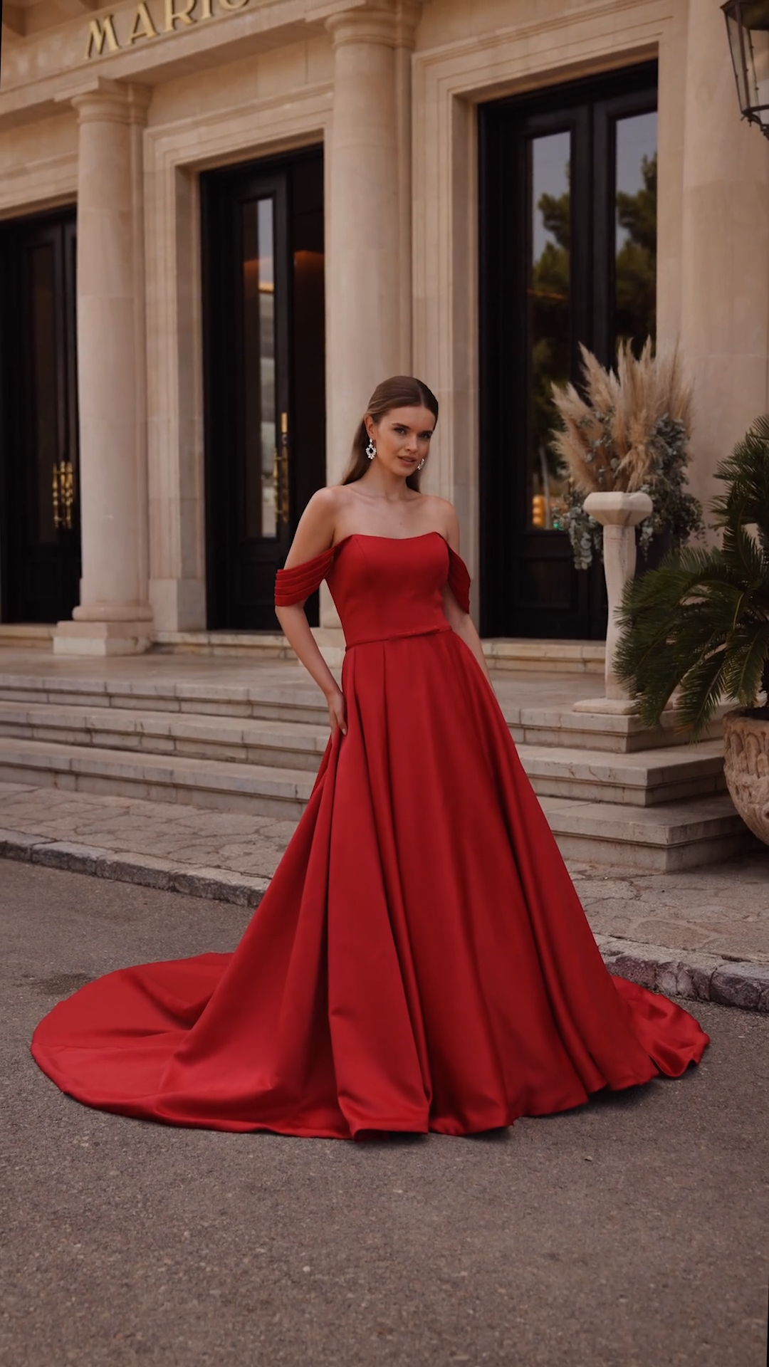 Bride wearing a red satin A-line wedding dress with off the shoulder pleated sleeves