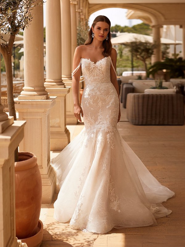 Bride walking in lace applique drop waist wedding dress with pointed sweetheart neckline and triple strand off the shoulder strands