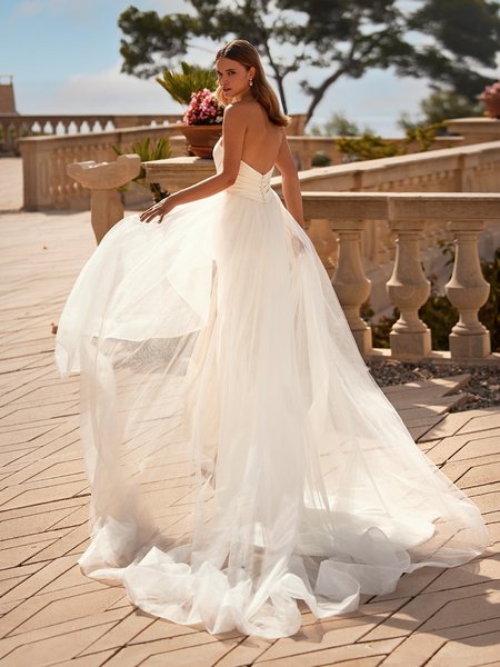 Bride walking away in strapless open neckline crepe wedding dress with cascade tulle train