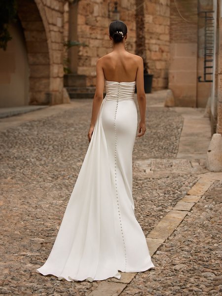 Bride walking away in a strapless crepe wedding dress with pleated bodice and sweep train