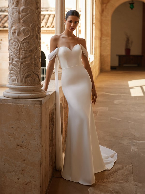 Bride wearing a sweetheart crepe wedding dress with chiffon off the shoulder streamers
