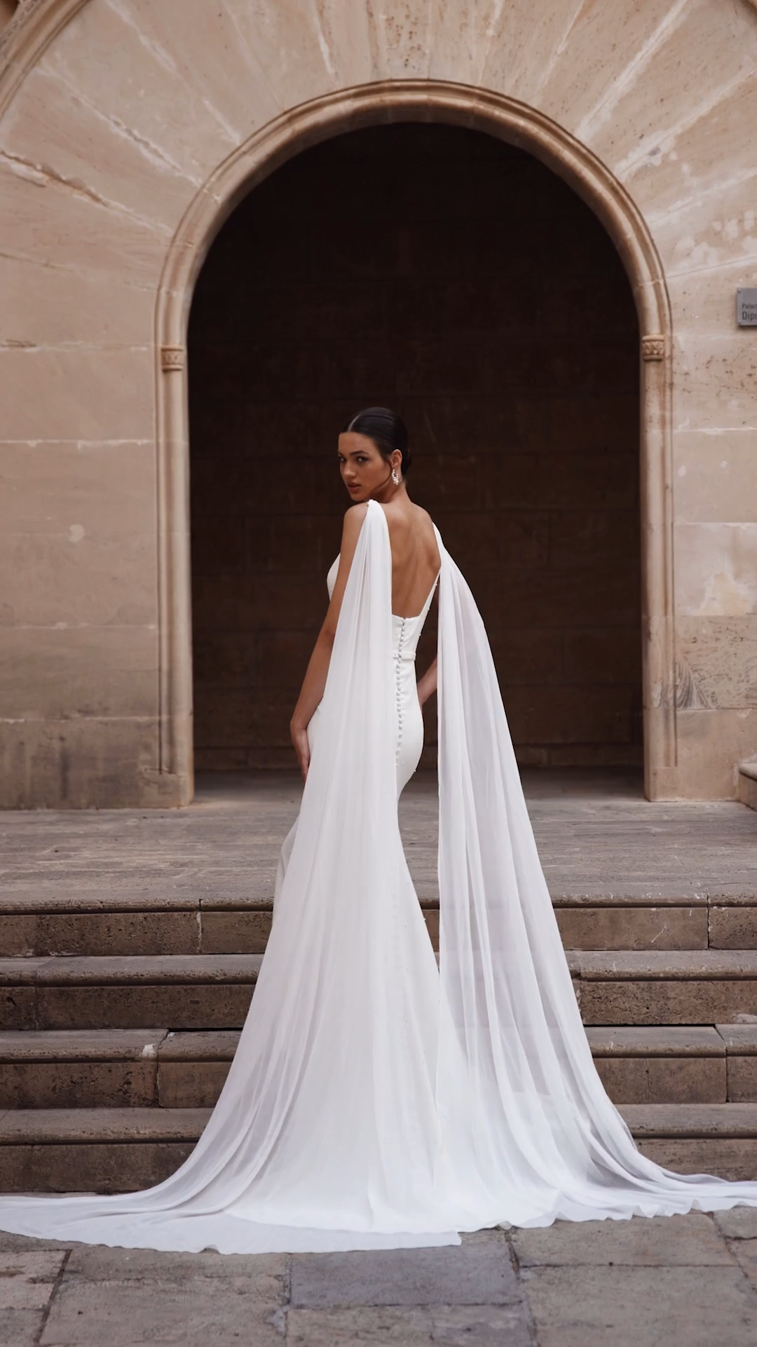 Bride wearing a deep v-neckline pearl and crepe wedding dress with detachable chiffon wings