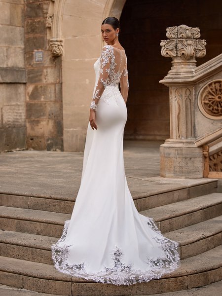 Bride walking up stairs in illusion back crepe wedding dress with long sleeve and lace scalloped train