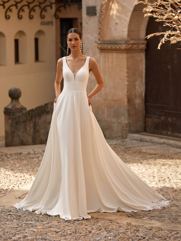 Bride walking in crepe wedding dress with tank straps and deep sweetheart neckline with cummerbund waistline